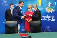Rafał Piech i Jarosław Wieczorek przekazują sobie podpisane umowy w obecności posła Jana Polaczka…