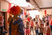 Plan pierwszy - klown. W tle dzieci bawiące się na sali