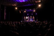 Widok od tyłu sali na widownię pełną fanów oraz muzyków zespołu Macieja Balcara na scenie
