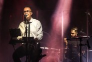 Na pierwszym planie Bartosz Zdechlikiewicz- wokalista zespołu Albo i Nie. Siedzi na scenie,…