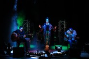 Widok na scenę oświetloną kolorowymi światłami. Na scenie troje muzyków zespołu Mikromusic.…