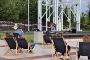 Adam Bul gra na gitarze pod szybem, wokoło ludzie słuchają go siedząc na leżakach