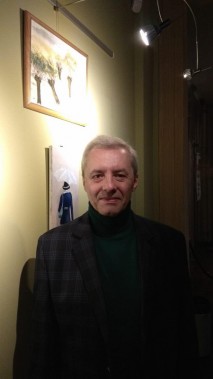 Mężczyzna w średnim wieku, ubrany w zielony golf i szarą marynarkę