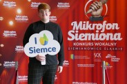 Błażej Klimaszka na tle czerwonej ścianki reklamowej konkursu