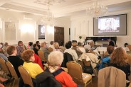 Sala Lustrzana siedząca publiczność za stołem siedzi prelegent na ekranie slajd z widokiem…