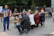 Zgromadzeni goście śpiewają przy akompaniamencie stojącego akordeonisty