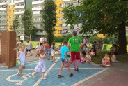 Grupa dzieci biegnąca w kółku za aktorem na parkingu, z zaznaczonym na niebesko prostokątem -…