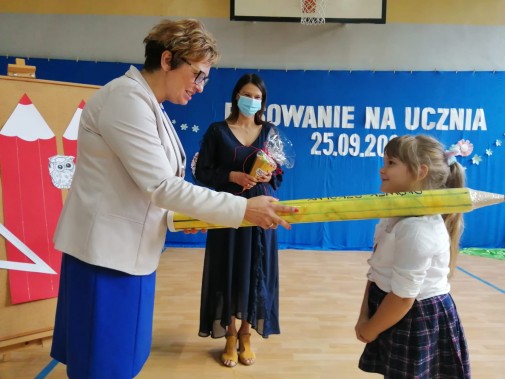 Pani dyrektor pasuje dziewczynkę na uczennicę pierwszej klasy