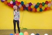 Na żółtym tle sceny amfiteatru wiszą kolorowe balony. Na scenie występuje Julia Krupa, wokalistka…
