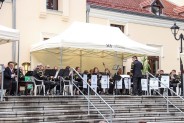 Pod białym namiotem siedzą członkowie Orkiestry Dętej z Bytomia ubrani w górnicze stroje, z lewej…
