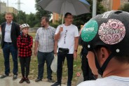 Zbliżenie na kask rowerzysty. W tle rozmazane postacie.