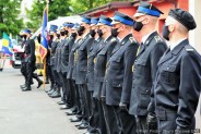 Strażacy w mundurach galowych stoją w szeregu w czasie uroczystej zbiórki z okazji Dnia Strażaka
