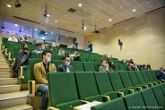 Widok na publiczność w Parku Tradycji. Uczestnicy siedzą oddaleni od siebie i czekają na swoją…