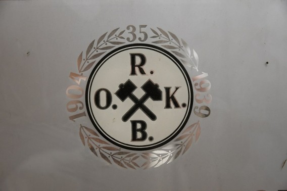 Przedstawia front kalendarza, na szaro-srebrnym tle widoczne logo zawierające dwa skrzyżowane…