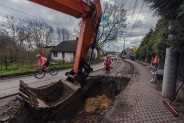 Ulica Wiejska z rozkopaną nawierzchnią. Po lewej stronie fragment koparki w trakcie prac ziemnych.