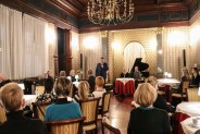 Widok z tyłu na salę widowiskową Willi Fitznera podczas imprezy. Ludzie siedzą przy stolikach i…