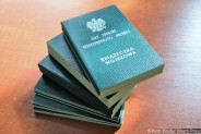 Stos książeczek wojskowych leży na blacie biurka