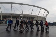 Mechatronicy na rowerach na tle stadionu
