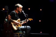 Siedzący mężczyzna grający na gitarze