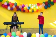 Na żółtym tle sceny amfiteatru wiszą kolorowe balony. Na scenie występują podopieczni MDK Jordan