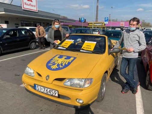 Dwoje radnych przy żółtym samochodzie