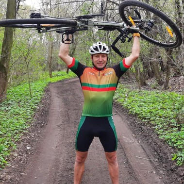 Tomasz Dzierga trzymający rower nad głową.