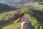 Widok na góry. Na planie pierwszym duża polana z gospodarstwem agroturystycznym