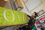 Dyrektor szkoły nadzoruje prace nad obrazem z logo szkoły.