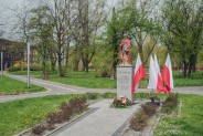 Figura św. Floriana ze złożonymi pod nią wiązankami kwiatów