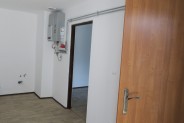 Wnętrze wyremontowanego lokalu socjalnego z białymi ścianami i beżową podłogą. Na pierwszym…