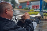 Muzyk gra na trąbce, w tle Kompleks Sportowy "Michał"