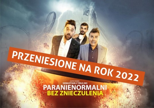 W wagoniku rollercoastera stoją trzej mężczyźni. Dwaj z przodu mają przerażone miny, trzeci z…