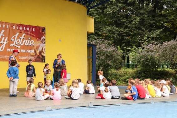Animacje dla dzieci na scenie amfiteatru. Widzimy z daleka scenę na której siedzą dzieci,…