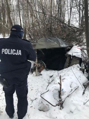 Policjant przy ziemiance bezdomnego