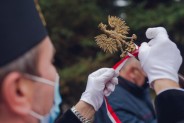 Górnik wiąże biało-czerwoną wstążkę na drzewcu sztandaru.