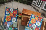 Na tarasie Biblioteki na dwóch kwiecistych leżakach leżą książki o parkach narodowych. Z tyłu…