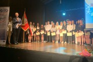 Uczniowie i nauczyciele staja na scenie.