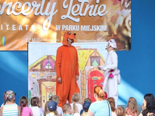Aktorzy przebrani za brązowego pieska i białego kotka ogrywają spektakl przed siedzącymi na…