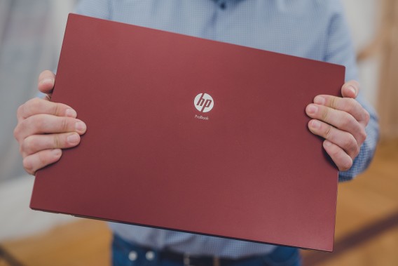 Bordowy laptop trzymany w dłoniach.