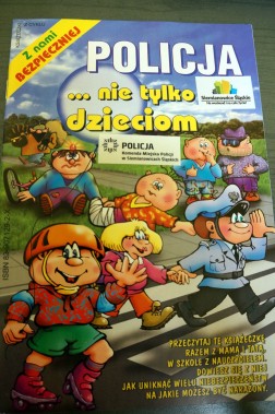 Okładka: policjant pokazuje dzieciom bezpieczne przejście przez ulicę
