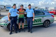 Tomasz Dzierga w towarzystwie dwóch policjantów. Za nimi stoi wóz policyjny.